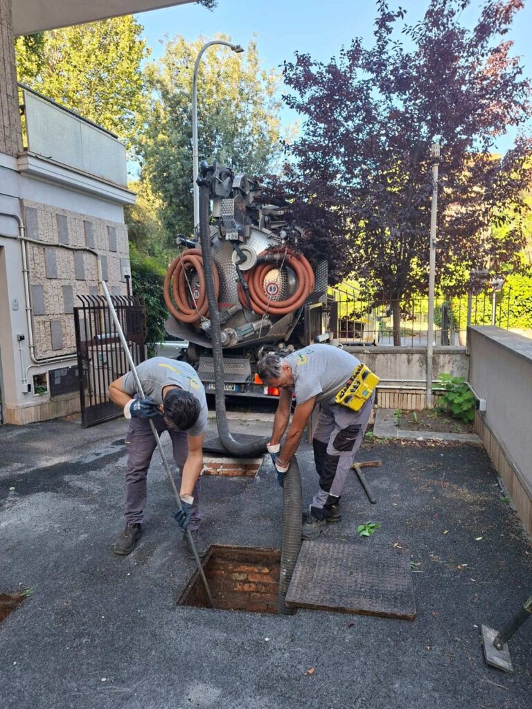 Tecnici al lavoro su un pozzetto della rete fognaria.